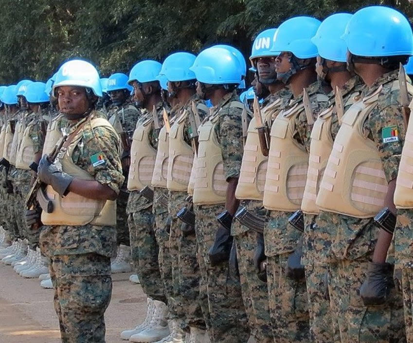 UN security team in camouflage and blue helmets with guns and bulletproof vests presumably in Africa
