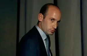 Steven Miller in blue suit and gray tie looking mischievously at the camera